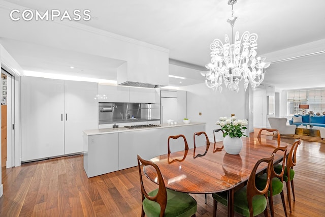 dining room with ornamental molding, light wood-style flooring, and an inviting chandelier