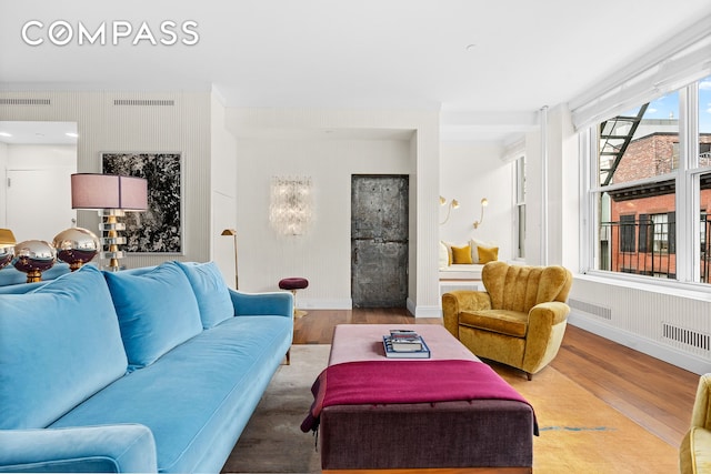 living room featuring baseboards, visible vents, and wood finished floors