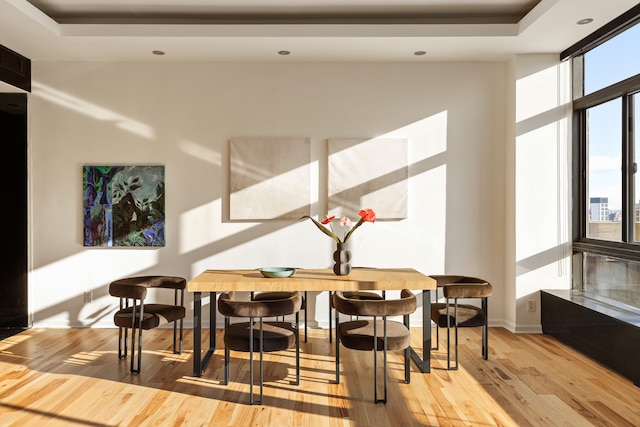 dining area with expansive windows, a raised ceiling, wood finished floors, and recessed lighting