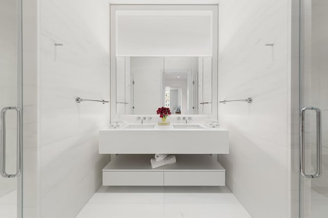 bathroom featuring double vanity, a stall shower, and a sink