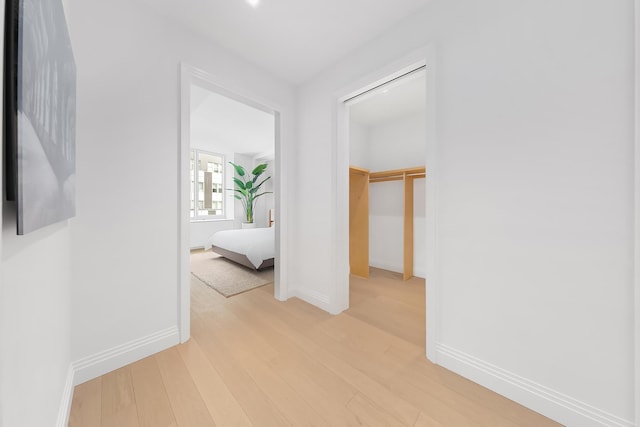 corridor featuring light wood finished floors and baseboards