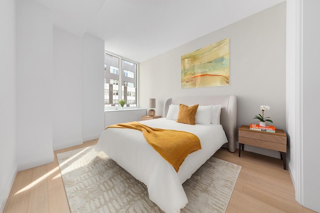 bedroom with light wood finished floors and baseboards