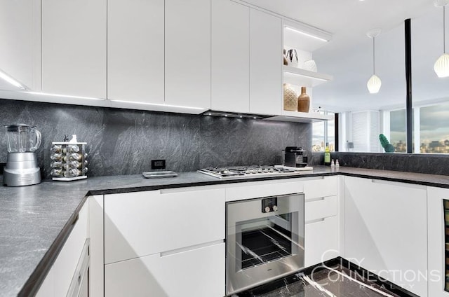 15 W 63rd St Unit 21-A, New York City, NY 10023 - kitchen with gas stovetop, oven, backsplash, dark countertops, and white cabinets