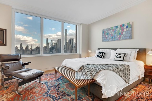 bedroom with ornamental molding, wood finished floors, and a city view