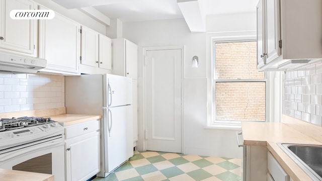 kitchen with light countertops, a sink, white cabinets, light floors, and white appliances