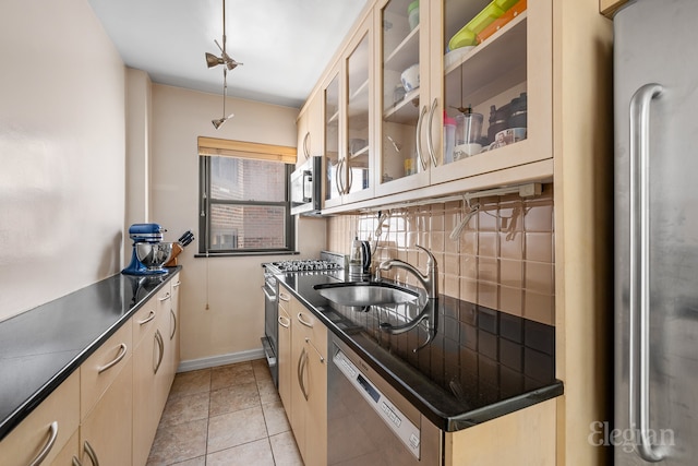 kitchen with appliances with stainless steel finishes, dark countertops, a sink, and tasteful backsplash