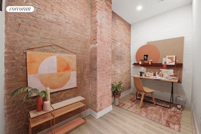 home office with brick wall, wood finished floors, and baseboards