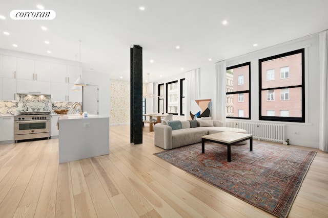 living area with radiator, visible vents, and light wood finished floors