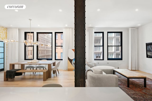 dining room featuring radiator, a notable chandelier, wood finished floors, and visible vents