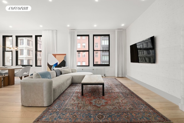 living room featuring wood finished floors, visible vents, recessed lighting, and radiator