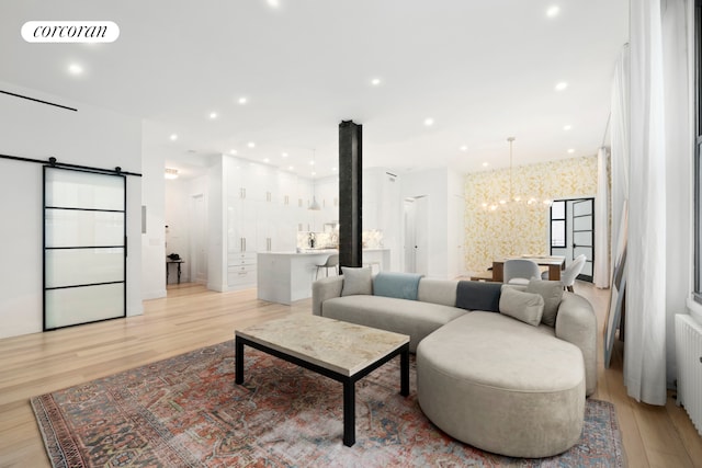 living area featuring a chandelier, a barn door, recessed lighting, visible vents, and light wood finished floors