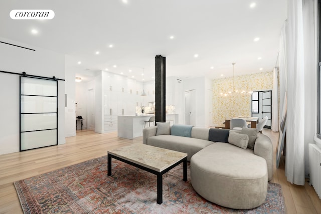 living area featuring a barn door, light wood-style floors, visible vents, and a chandelier
