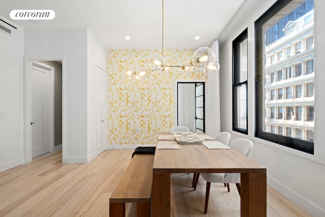 dining area featuring light wood finished floors, visible vents, an inviting chandelier, baseboards, and wallpapered walls