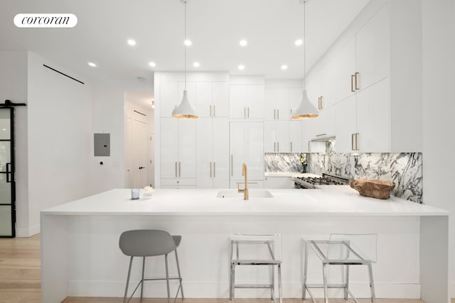 kitchen with light countertops, visible vents, a barn door, a sink, and a peninsula