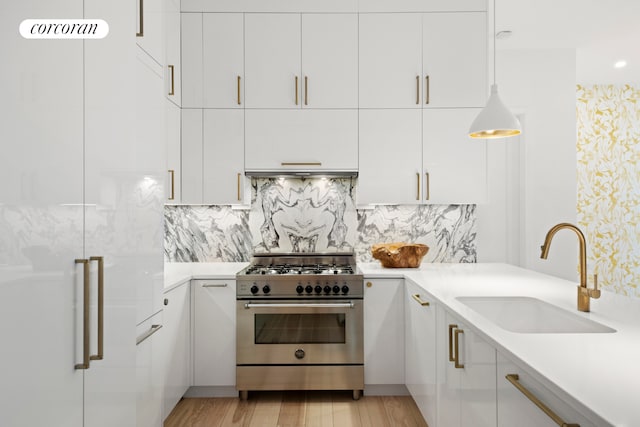 kitchen featuring stainless steel stove, a sink, white cabinetry, and light countertops