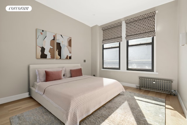 bedroom with radiator, visible vents, baseboards, and wood finished floors