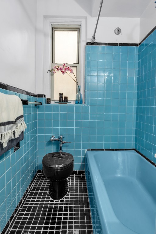 full bath featuring tile patterned flooring and tile walls