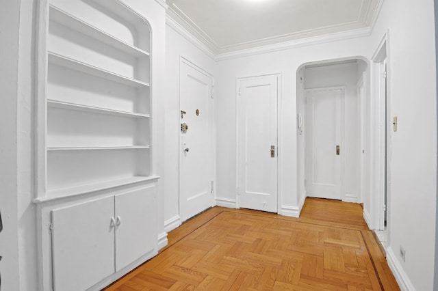 corridor featuring crown molding, baseboards, and arched walkways