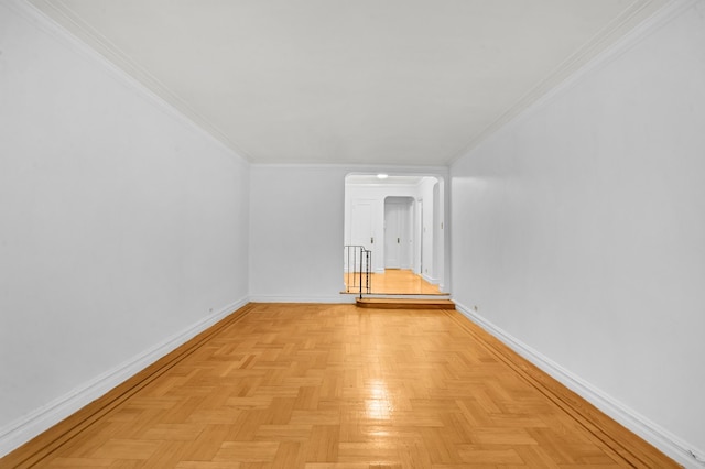 empty room featuring arched walkways, crown molding, and baseboards