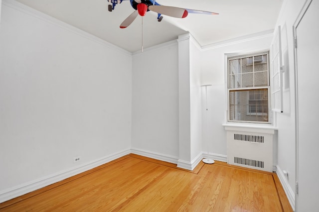 unfurnished room featuring radiator heating unit, ornamental molding, ceiling fan, wood finished floors, and baseboards