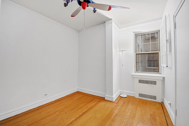spare room featuring radiator heating unit, a ceiling fan, wood finished floors, ornamental molding, and baseboards