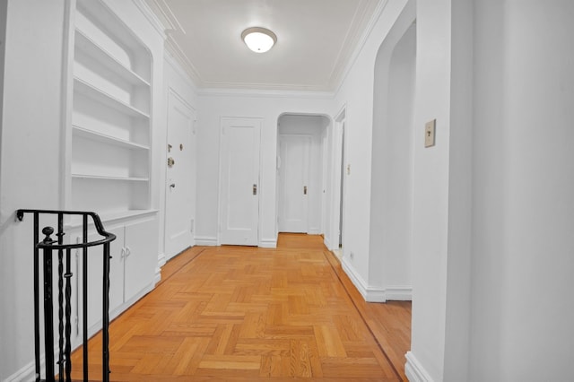 hall with arched walkways, ornamental molding, baseboards, and built in features