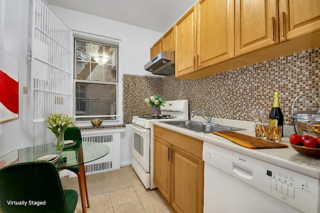 kitchen with radiator, light countertops, white gas stove, under cabinet range hood, and backsplash