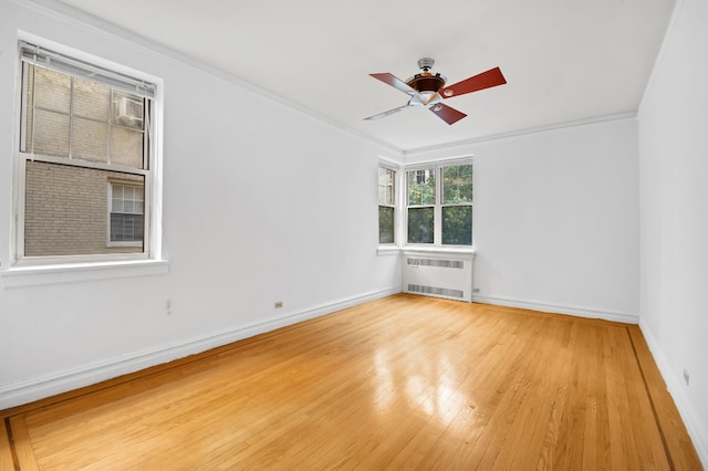 unfurnished room featuring light wood finished floors, radiator heating unit, a ceiling fan, ornamental molding, and baseboards