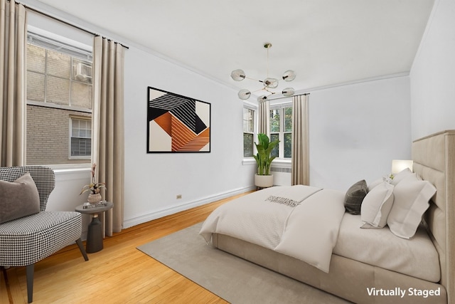 bedroom featuring wood finished floors, a chandelier, baseboards, and crown molding
