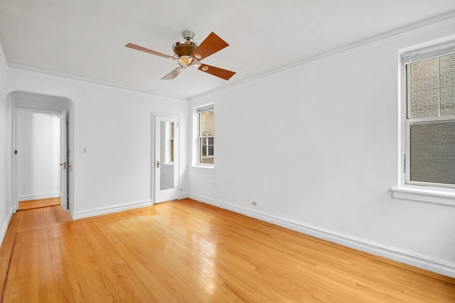 empty room featuring light wood-style floors, crown molding, baseboards, and ceiling fan