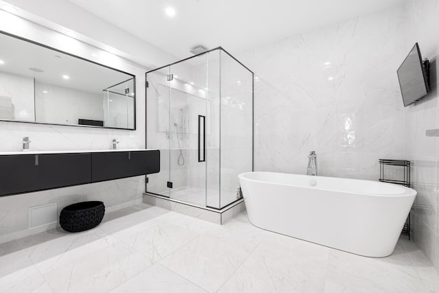 bathroom with double vanity, a marble finish shower, marble finish floor, a freestanding tub, and recessed lighting