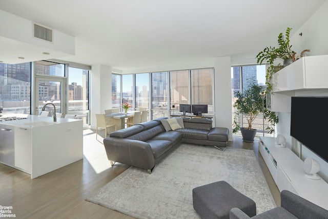 living area featuring floor to ceiling windows, visible vents, and light wood finished floors