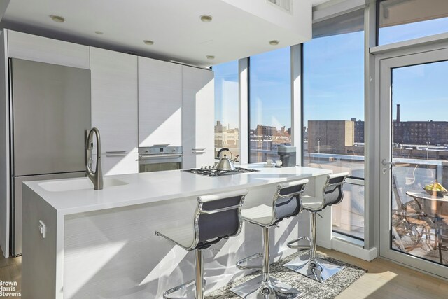 kitchen with light wood-style flooring, modern cabinets, appliances with stainless steel finishes, a view of city, and a sink