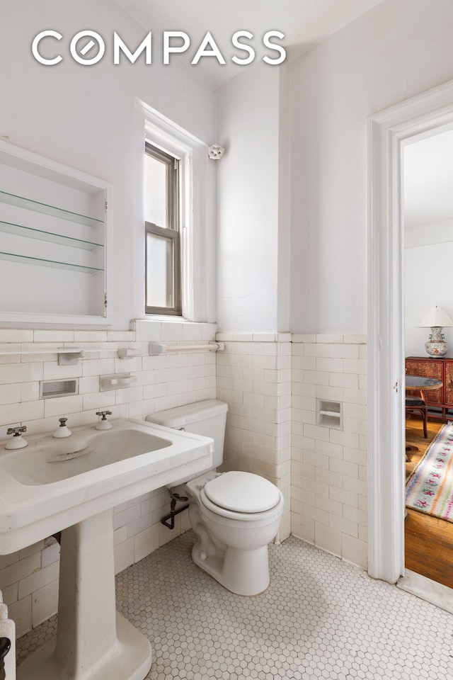 20 W 77th St Unit 15A, New York City, NY 10024 - bathroom with tile walls, toilet, a wainscoted wall, and tile patterned flooring