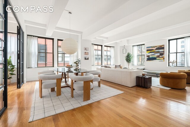 dining room featuring light wood-style floors and beamed ceiling