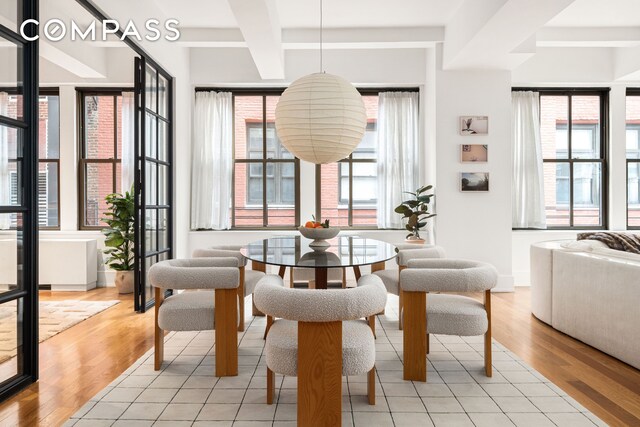 dining area with light wood-style flooring, baseboards, coffered ceiling, and beam ceiling