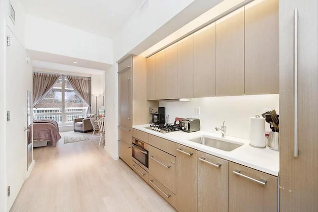 kitchen with light wood finished floors, visible vents, light countertops, appliances with stainless steel finishes, and a sink