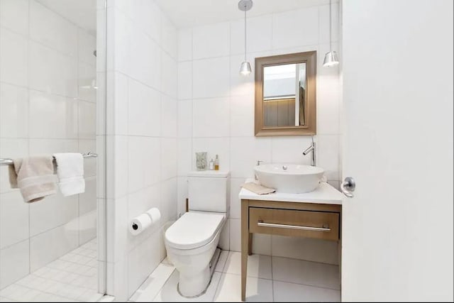 bathroom with toilet, tile walls, a shower stall, tile patterned flooring, and vanity