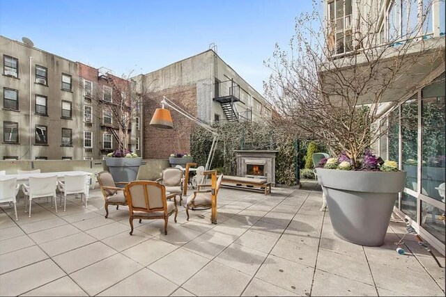 view of patio featuring a warm lit fireplace