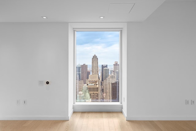empty room with baseboards, a city view, and wood finished floors