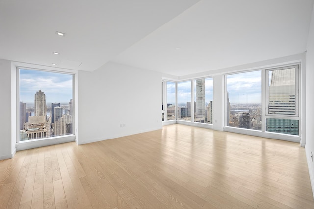 unfurnished living room with baseboards, a city view, and light wood-style flooring