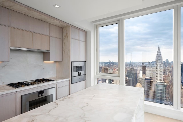 kitchen featuring light stone countertops, appliances with stainless steel finishes, tasteful backsplash, under cabinet range hood, and a warming drawer