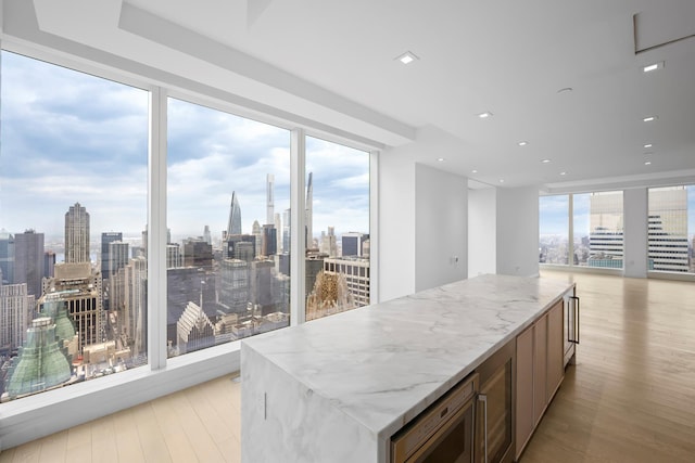 kitchen featuring light stone counters, stainless steel microwave, light wood-type flooring, and a center island