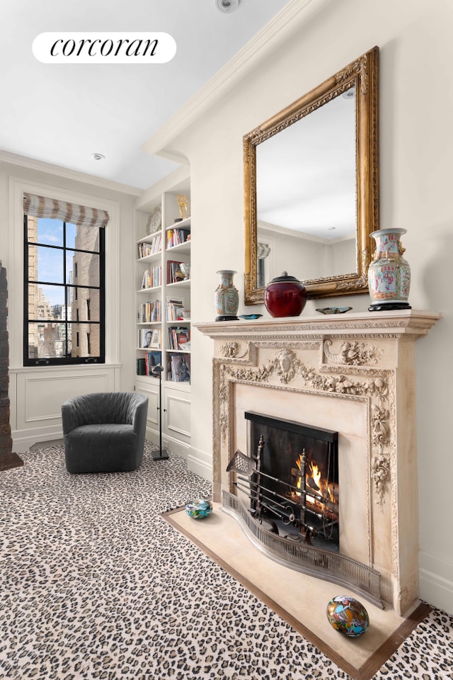 living room featuring a fireplace, baseboards, crown molding, and built in shelves