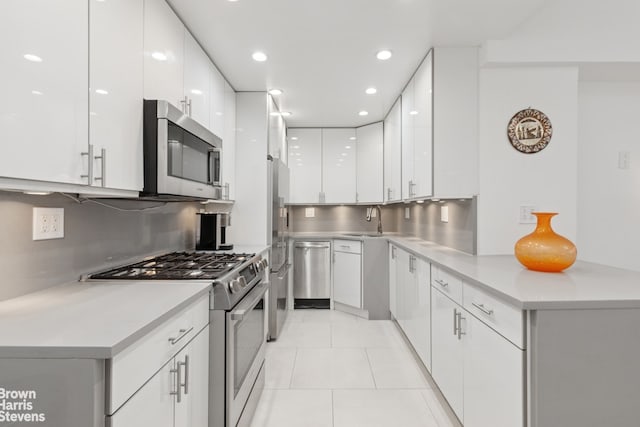 kitchen featuring light tile patterned floors, appliances with stainless steel finishes, white cabinets, and light countertops