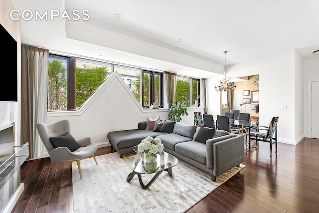 living area with dark wood-style floors, a notable chandelier, and baseboards