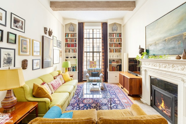 sitting room featuring a lit fireplace and beamed ceiling