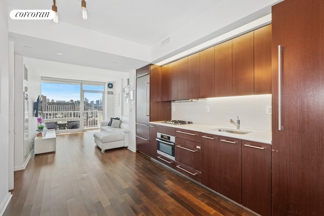 kitchen featuring stainless steel oven, a sink, gas stovetop, open floor plan, and dark wood-style floors