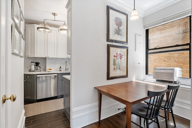 kitchen featuring dark wood finished floors, crown molding, light countertops, decorative backsplash, and stainless steel dishwasher