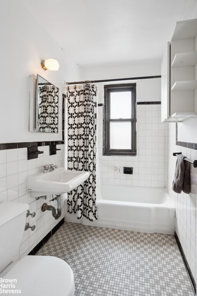 full bath with toilet, a sink, tile walls, and shower / bathtub combination with curtain